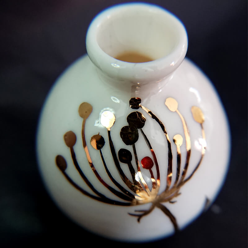 A tiny fine porcelain vase with glazed 24 carat gold flower painting.  